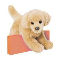 A yellow dog plush sitting over a peach-colored wall.