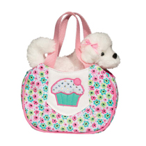 A cute white dog in a pastel bag with a cupcake on it.