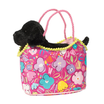 A black lab in a hand bag with a flower pattern on it.